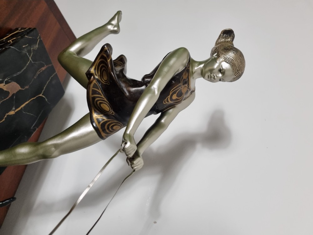 An Art Deco sculpture depicting a silvered female figure running alongside two dark greyhounds, mounted on a black marble base. View V