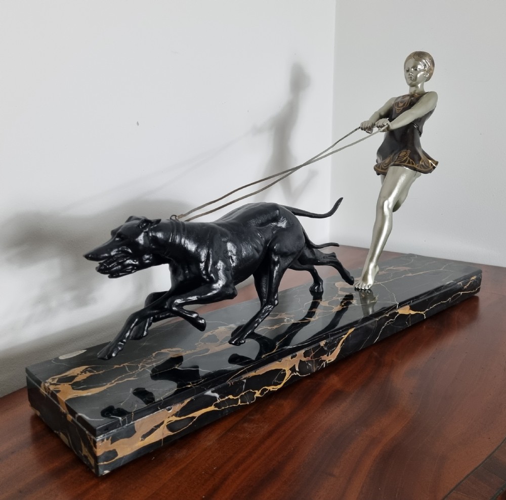 An Art Deco sculpture depicting a silvered female figure running alongside two dark greyhounds, mounted on a black marble base. View XI