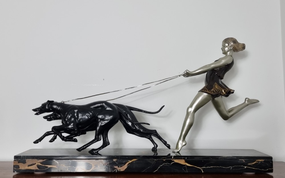 An Art Deco sculpture depicting a silvered female figure running alongside two dark greyhounds, mounted on a black marble base. View XV