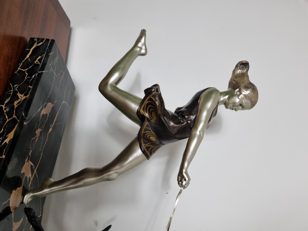 An Art Deco sculpture depicting a silvered female figure running alongside two dark greyhounds, mounted on a black marble base. View XVI