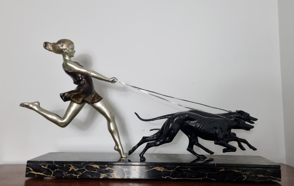 An Art Deco sculpture depicting a silvered female figure running alongside two dark greyhounds, mounted on a black marble base. View XVIII
