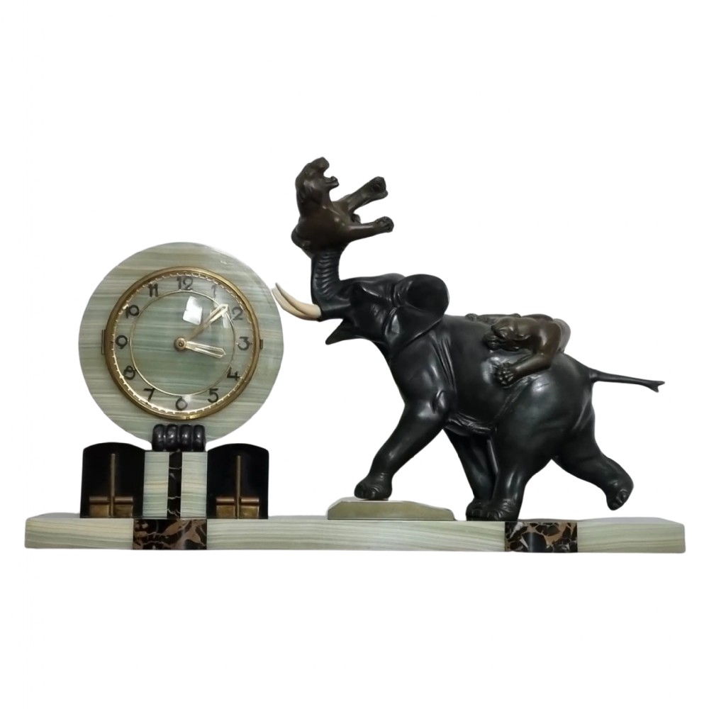 An Art Deco mantel clock featuring a circular green onyx dial flanked by dark patinated spelter sculptures of an elephant and panthers on a layered marble base.