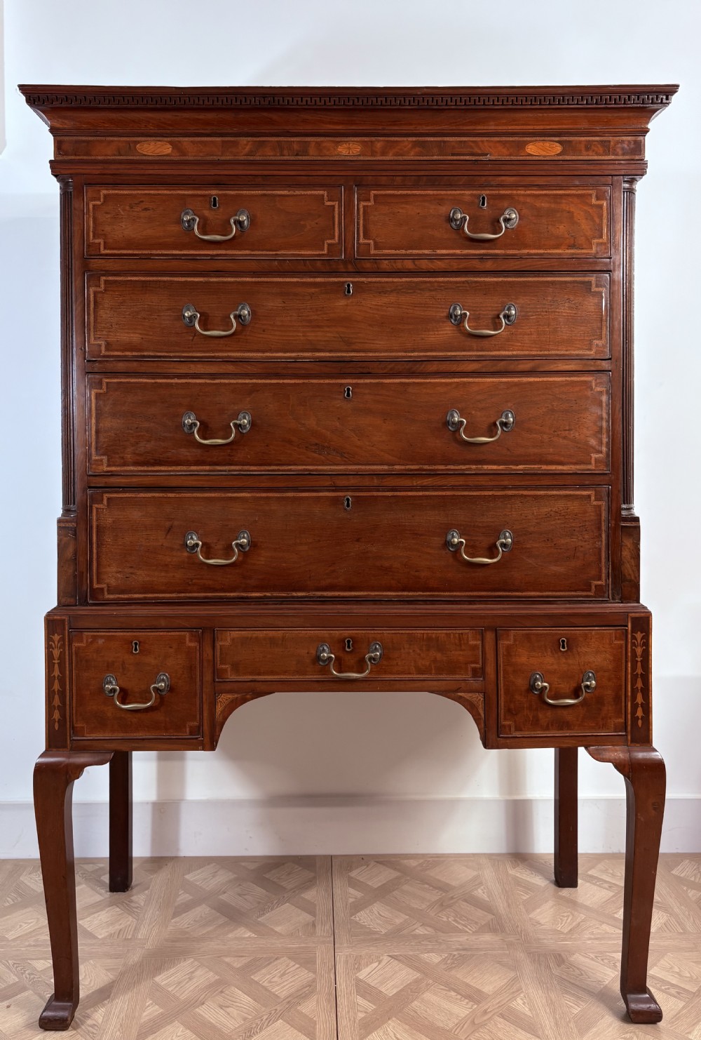 An eighteenth-century mahogany chest on stand featuring satinwood inlay, brass handles, a dentil moulding cornice, and cabriole legs. View II