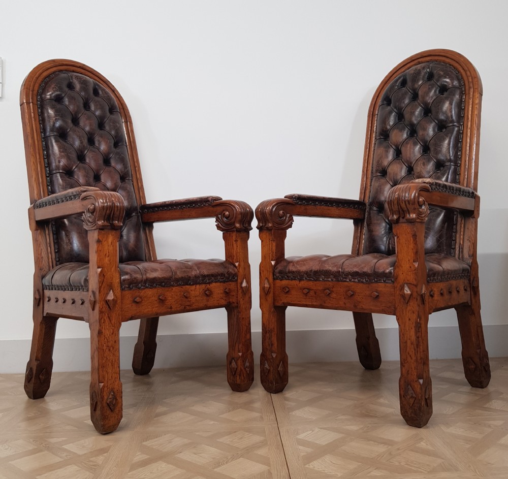 A pair of 19th-century Gothic Revival oak armchairs featuring arched high backs with deep buttoned dark brown leather upholstery and carved armrests. View II