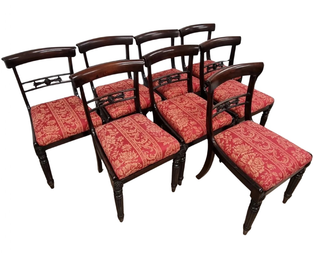 A set of eight 19th-century William IV rosewood dining chairs featuring carved crossbars, turned front legs, and red patterned upholstered seats.