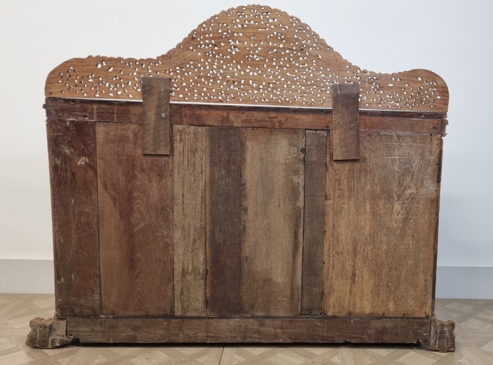 A 19th-century Anglo-Indian intricately carved teak wood cabinet featuring openwork floral lattice panels, figure pilasters, arched cresting, and carved animal feet. View V