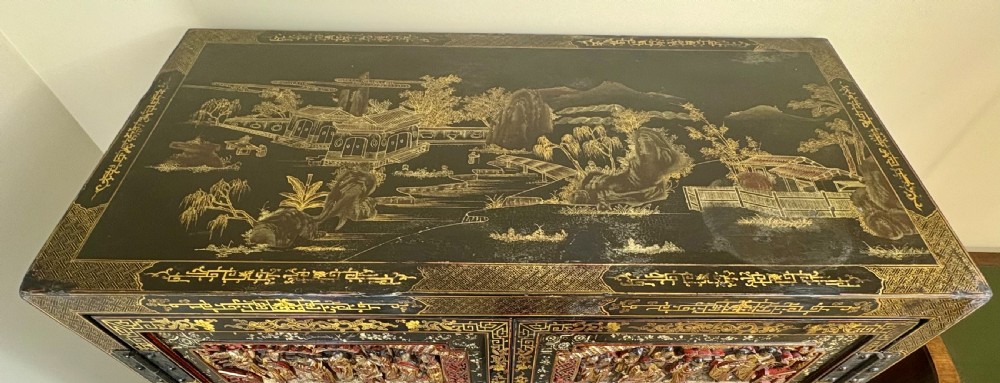 Late 19th-century Chinese black lacquer cabinet featuring intricate hand-carved polychrome figures, gilded panels of warriors on horseback, and brass door fittings. View III