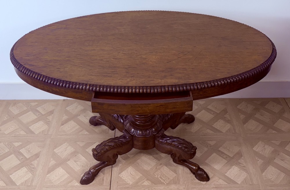 A circular Regency burr walnut centre table featuring a carved spiral pedestal and a four-legged base with carved animal feet. View IV