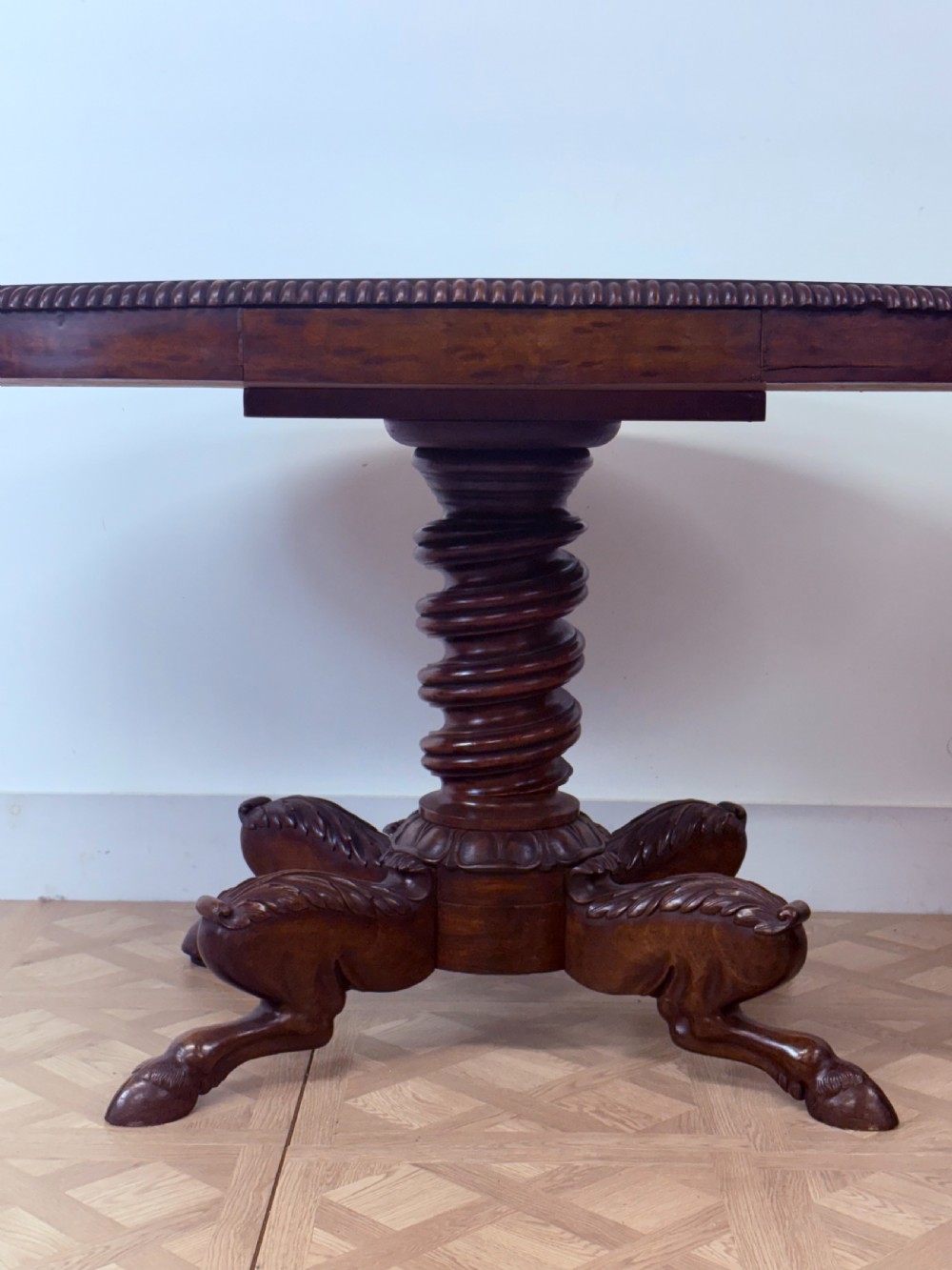 A circular Regency burr walnut centre table featuring a carved spiral pedestal and a four-legged base with carved animal feet. View V