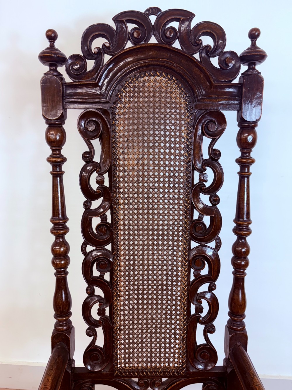 A late 17th-century Carolean dark walnut armchair featuring an intricately carved cresting rail, high caned back panel, curved arms, and turned legs. View IV