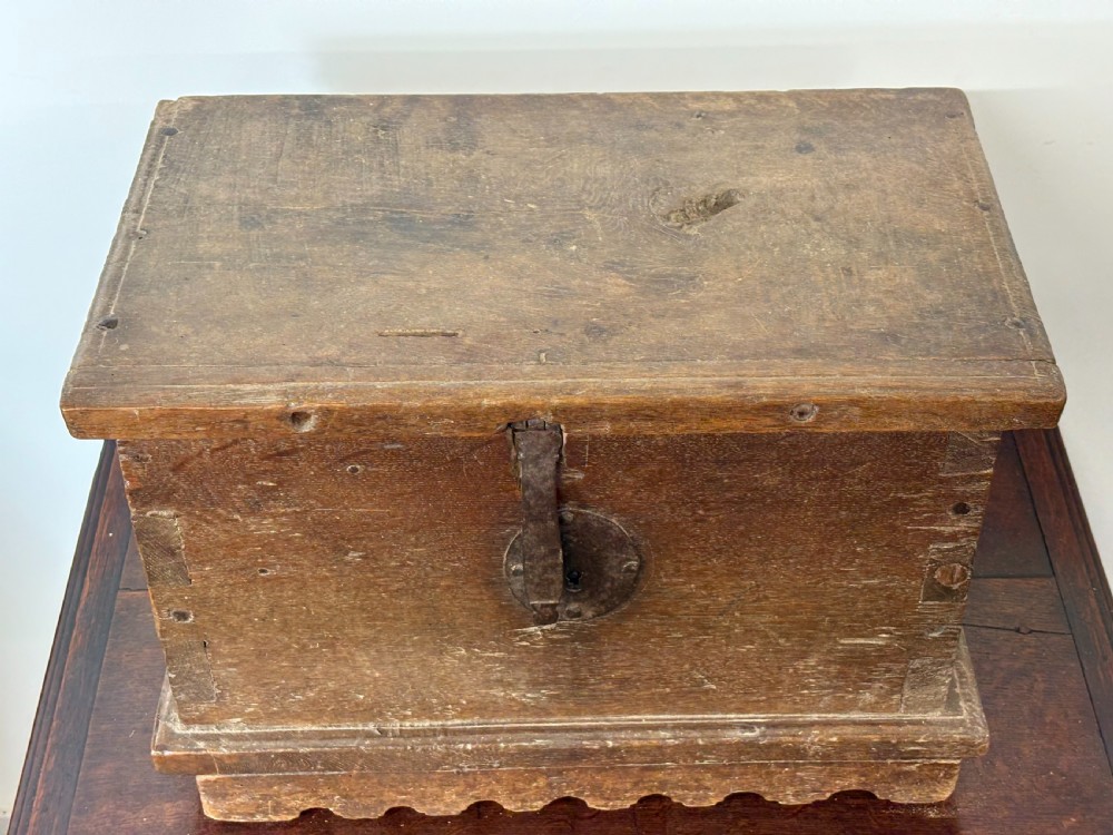 A late sixteenth to early seventeenth-century Flemish oak coffer featuring hand-forged iron clasp hardware, wooden pegs, and a scalloped base plinth. View II
