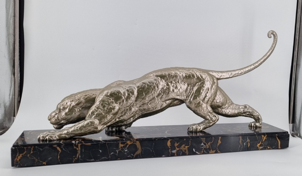 A low-slung, textured silver-toned panther in a crouched hunting posture mounted on a black marble base with gold veining. View V
