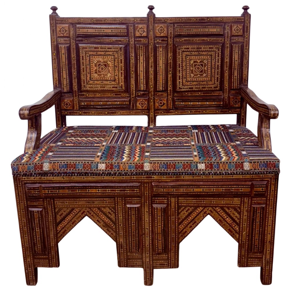 A 19th-century double-back Syrian hardwood bench featuring intricate geometric bone and timber parquetry inlay with a patterned upholstered seat.
