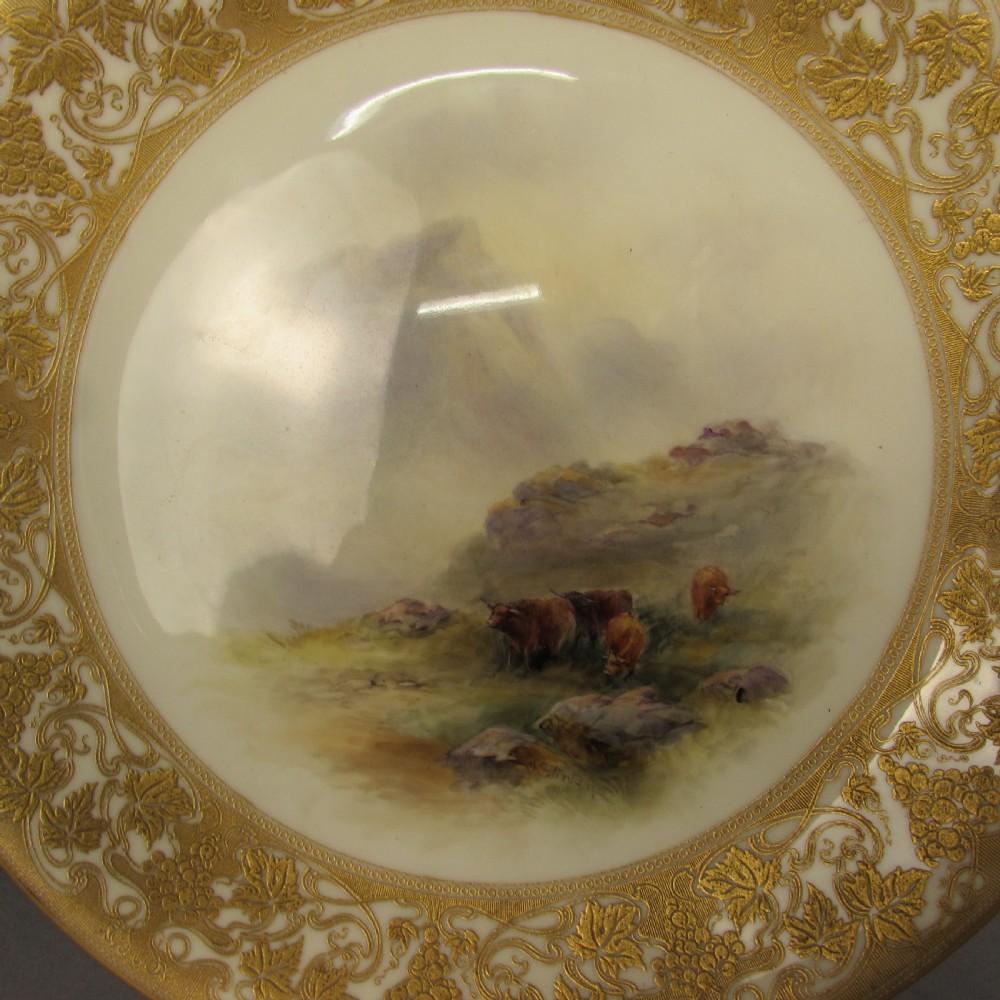 A pair of round Royal Worcester porcelain cabinet plates featuring hand-painted scenes of cattle in landscapes, bordered by ornate gold scrollwork gilding on a cream ground. View III
