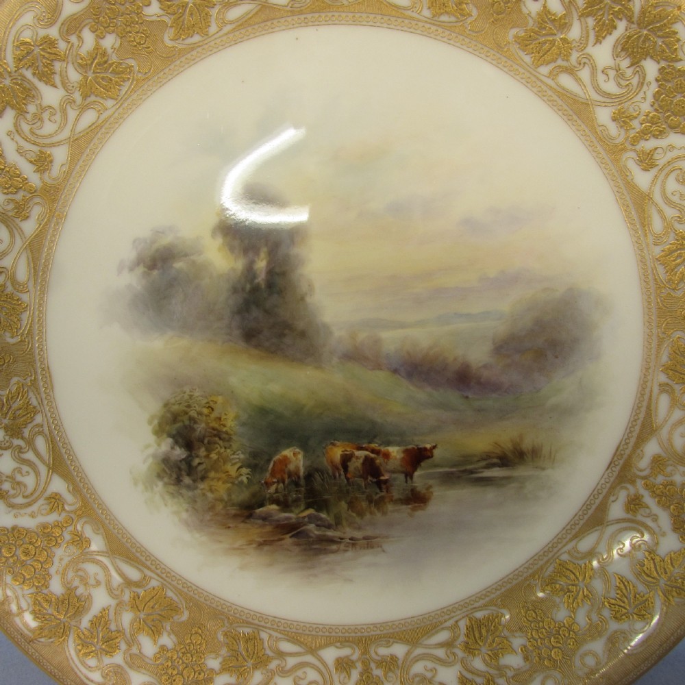 A pair of round Royal Worcester porcelain cabinet plates featuring hand-painted scenes of cattle in landscapes, bordered by ornate gold scrollwork gilding on a cream ground. View IV