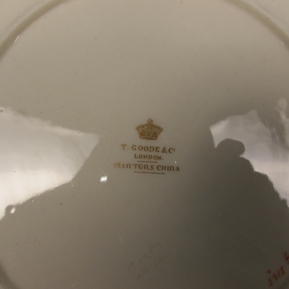 A circular cream porcelain cabinet plate featuring a central black octagonal medallion with a white relief cherub figure framed by gold leaf swags and an ornate gilded border. View II