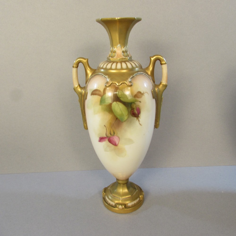 A hand-painted Royal Worcester porcelain vase featuring pink roses, twin gilded handles, and a flared neck on a pedestal base. View II