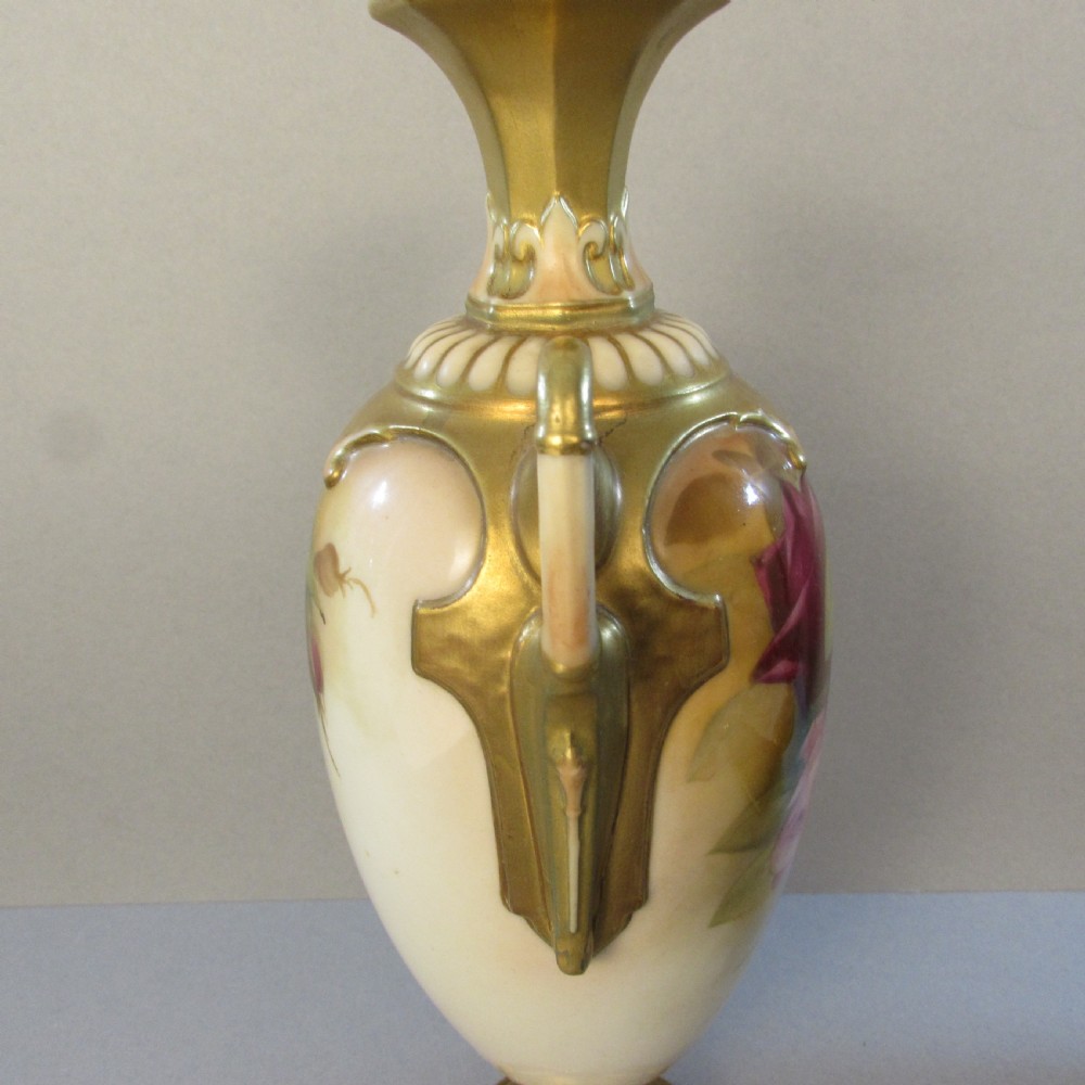 A hand-painted Royal Worcester porcelain vase featuring pink roses, twin gilded handles, and a flared neck on a pedestal base. View III