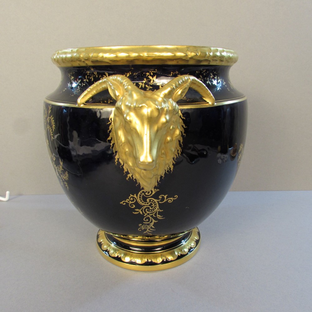 A cobalt blue porcelain jardiniere featuring gilded ram head handles, elaborate scroll gilding, and a central painted vignette of birds. View II