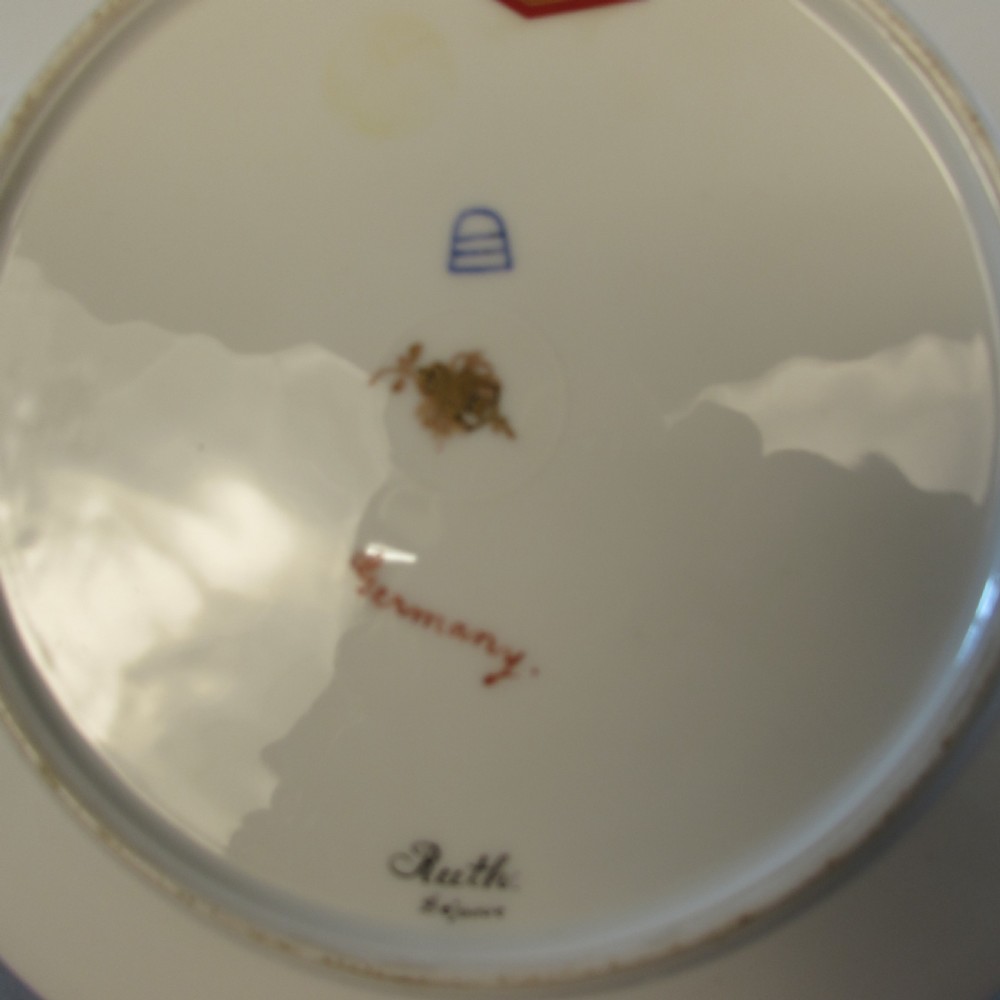 A circular porcelain cabinet plate featuring a central hand-painted portrait of a woman holding wheat, framed by a broad black rim decorated with gold leaf scrollwork. View II
