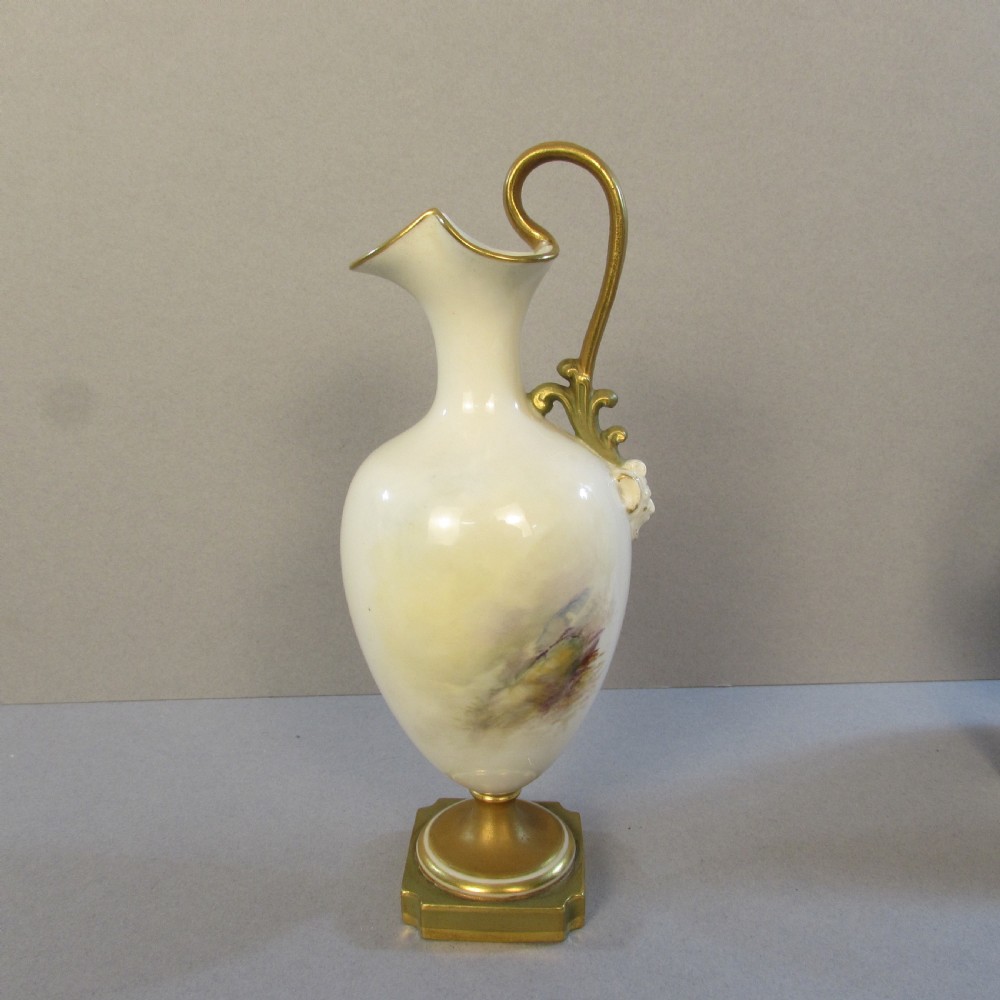 An ornate porcelain ewer featuring a hand-painted scene of Highland cattle, a flared spout, a gilded scroll handle, and a square gold-finished base. View III