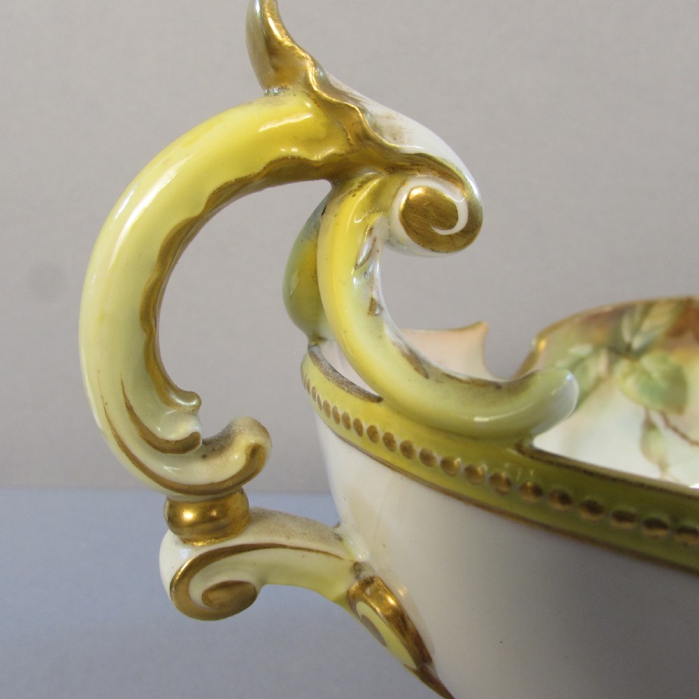A hand-painted Royal Worcester porcelain centrepiece bowl featuring yellow and red roses, scroll handles, and gilt detailing on a footed base. View III