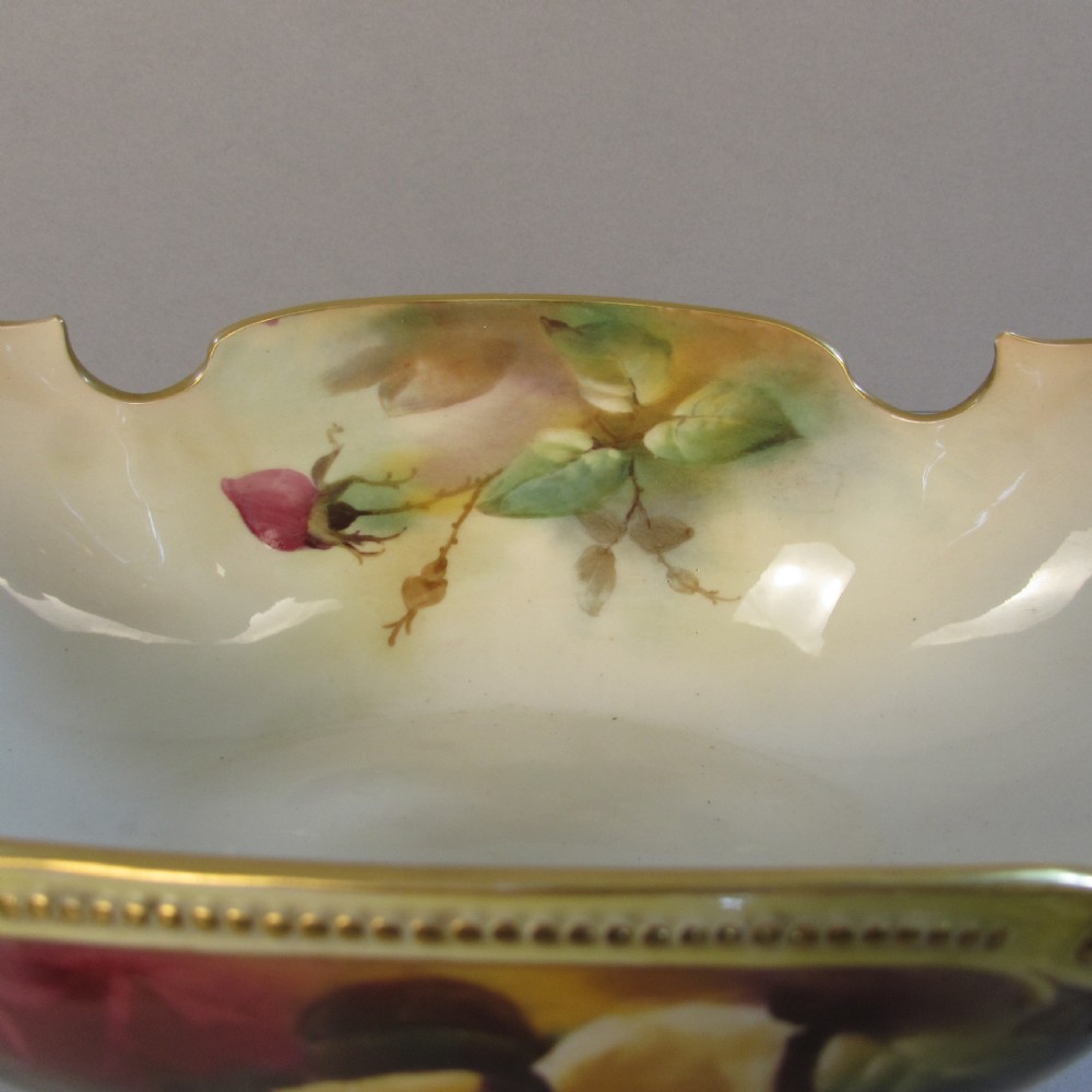 A hand-painted Royal Worcester porcelain centrepiece bowl featuring yellow and red roses, scroll handles, and gilt detailing on a footed base. View VI