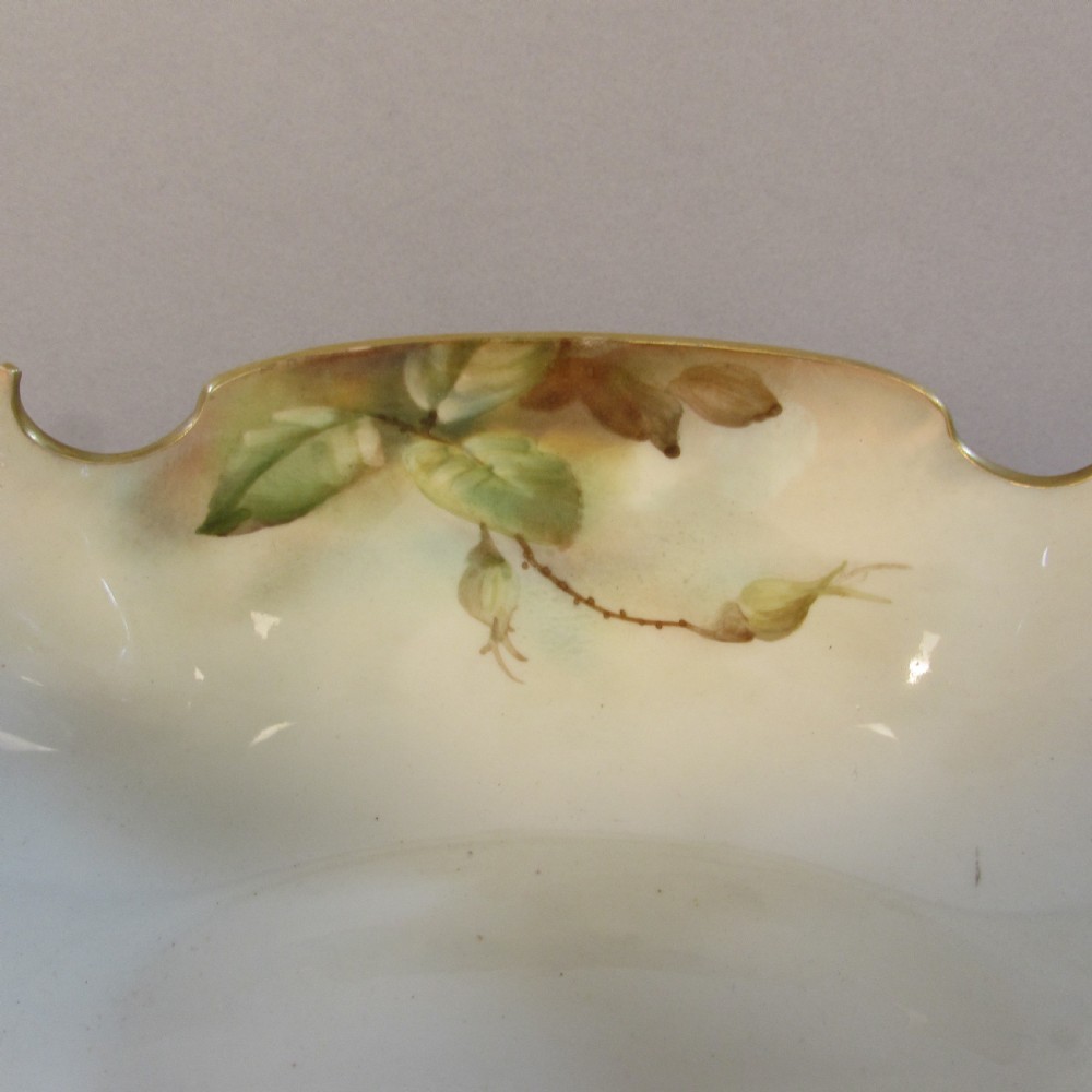 A hand-painted Royal Worcester porcelain centrepiece bowl featuring yellow and red roses, scroll handles, and gilt detailing on a footed base. View VII