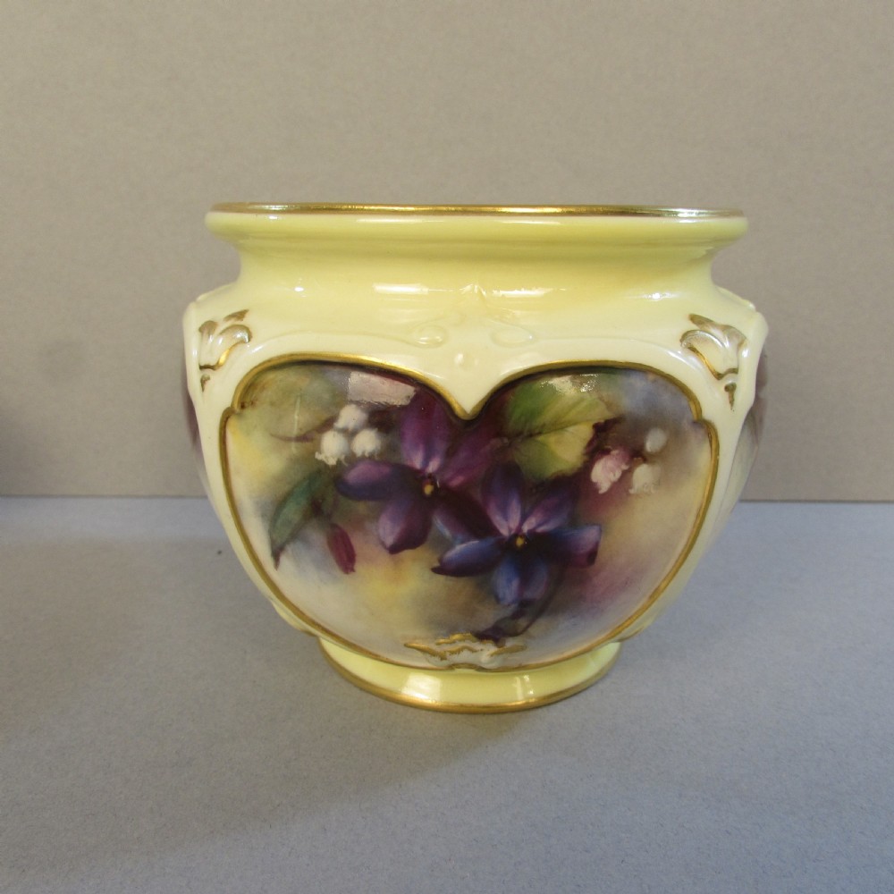 A small pale yellow porcelain vase featuring hand-painted purple flowers within a gold-trimmed shaped panel.