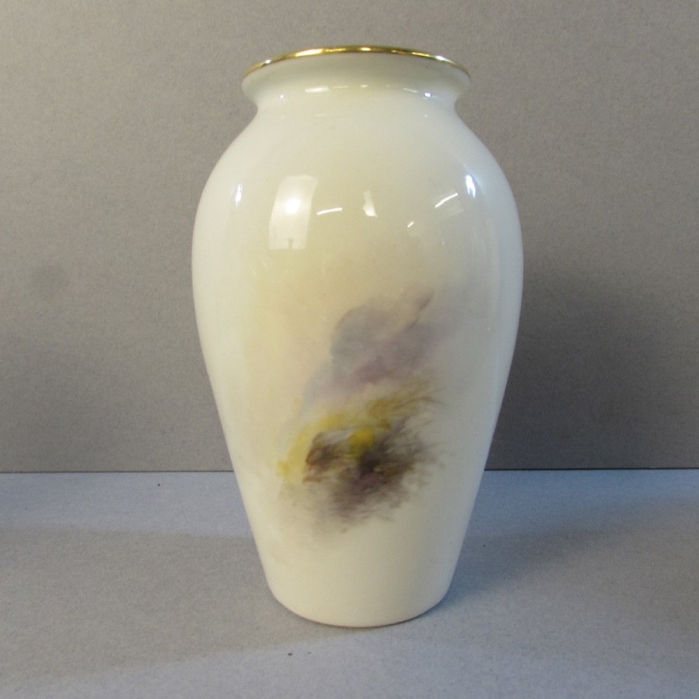 A cream baluster-shaped porcelain vase hand-painted with Highland cattle in a misty mountain landscape and finished with a gilt rim. View II