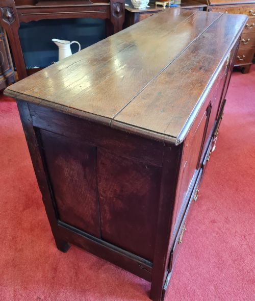 fig 1. An 18th-century dark oak mule chest featuring three raised fielded panels above three drawers with brass handles.