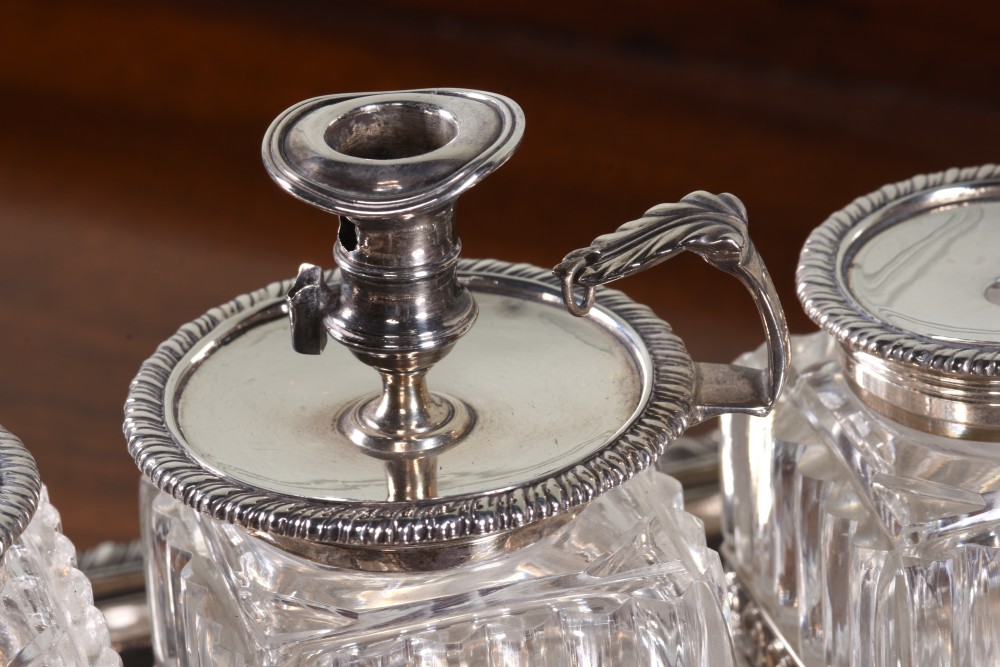 An Edwardian sterling silver desk stand with two cut-glass inkwells, a central chamber stick, and an engraved pen tray resting on paw feet. View III