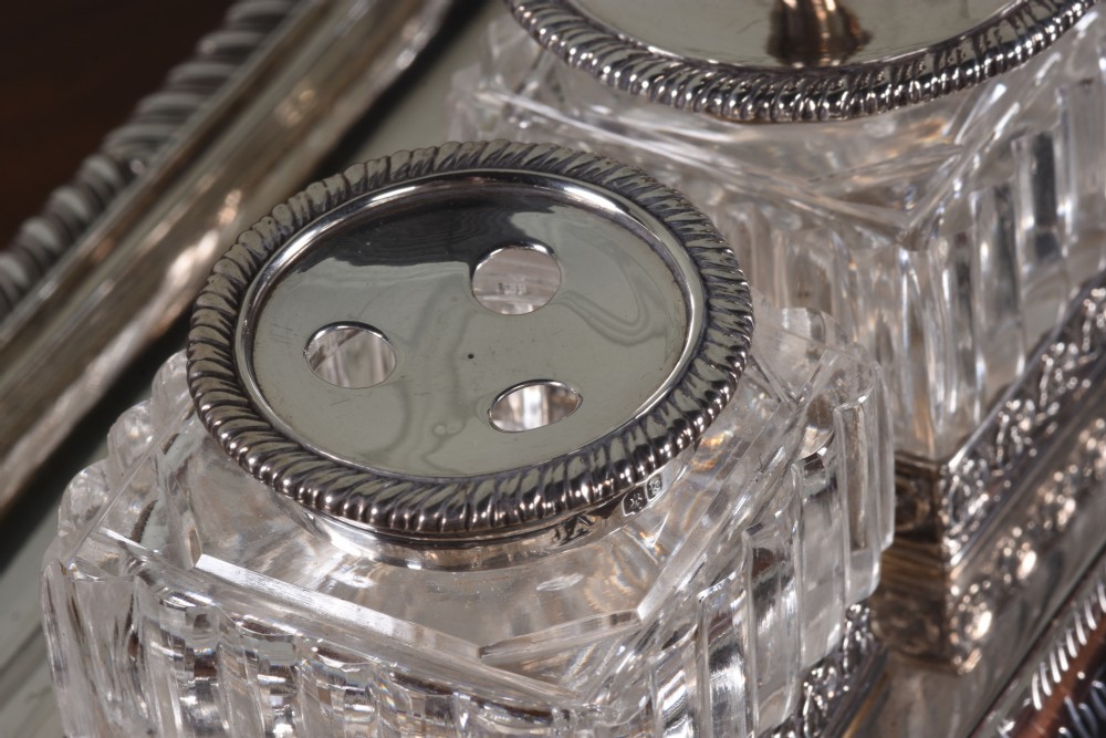 An Edwardian sterling silver desk stand with two cut-glass inkwells, a central chamber stick, and an engraved pen tray resting on paw feet. View IV