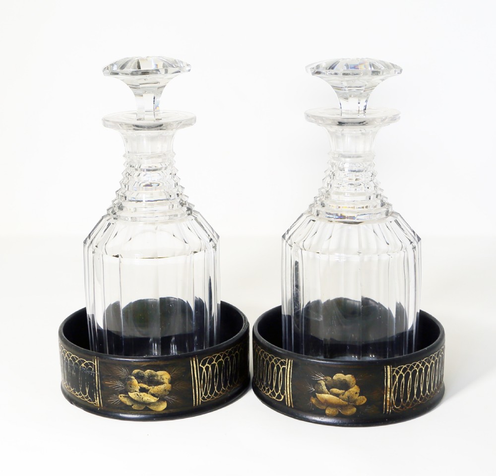 A pair of round black papier-mache coasters featuring hand-painted gold floral panels and looped decorative borders. View II