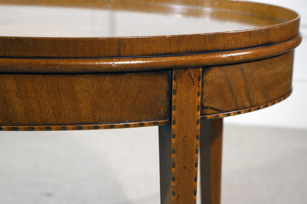 An oval mahogany low table featuring a raised gallery tray top, line inlay along the apron, and four square tapered legs. View II