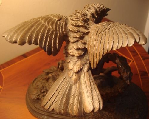 fig 2. A 19th-century bronze sculpture depicting a sparrow with raised wings perched on a branch atop a textured, oval-shaped base.