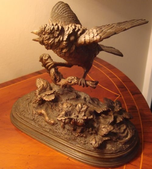 fig 3. A 19th-century bronze sculpture depicting a sparrow with raised wings perched on a branch atop a textured, oval-shaped base.