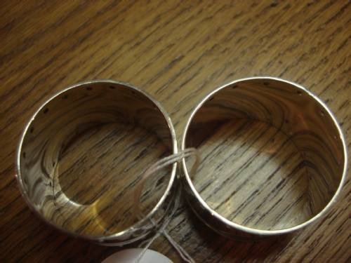 fig 1. A pair of circular sterling silver napkin rings featuring a studded border design and subtle engraved monograms.
