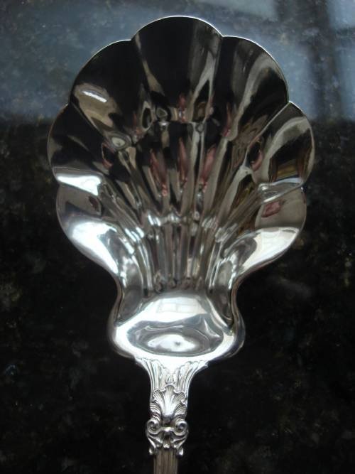 fig 2. An early twentieth-century sterling silver berry spoon featuring a fluted scallop shell bowl and an ornate embossed scroll handle.