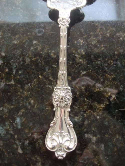 fig 3. An early twentieth-century sterling silver berry spoon featuring a fluted scallop shell bowl and an ornate embossed scroll handle.