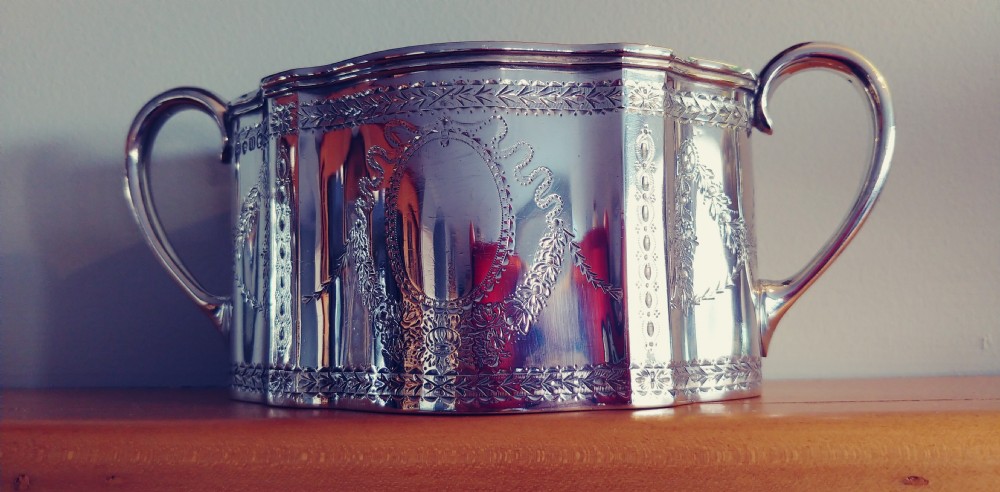 A Victorian sterling silver cream jug and matching double-handled sugar bowl featuring engraved garland motifs and curved handles. View II