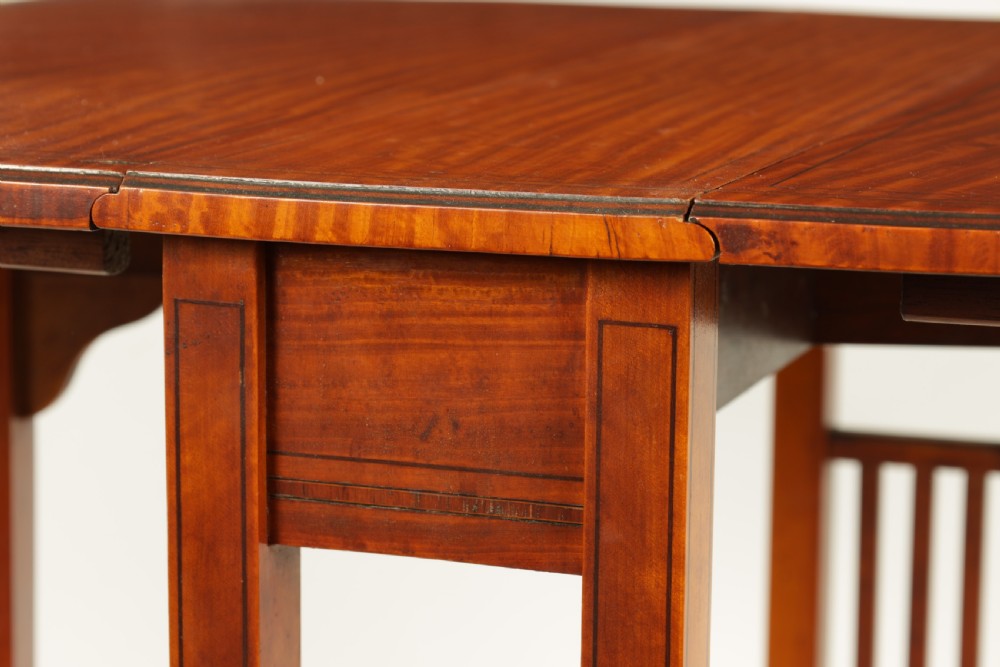 A nineteenth-century figured satinwood Sutherland table featuring two drop flaps, slatted upright legs, splayed feet, and small brass castors. View V