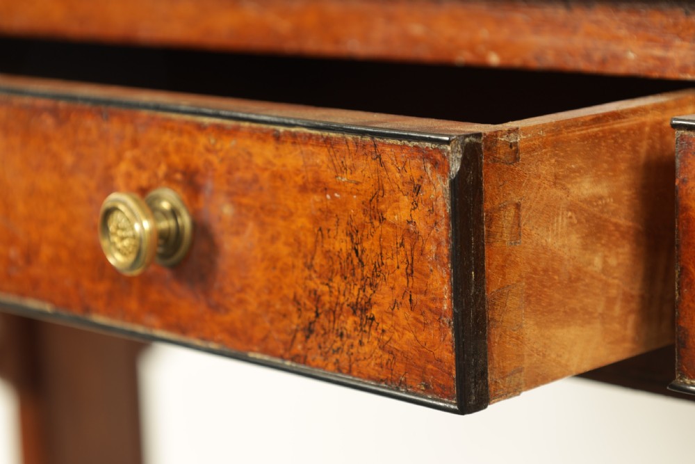 An antique amboyna and rosewood library table featuring a green leather inset top, frieze drawers with brass knobs, trestle legs, and carved lion paw feet. View VIII