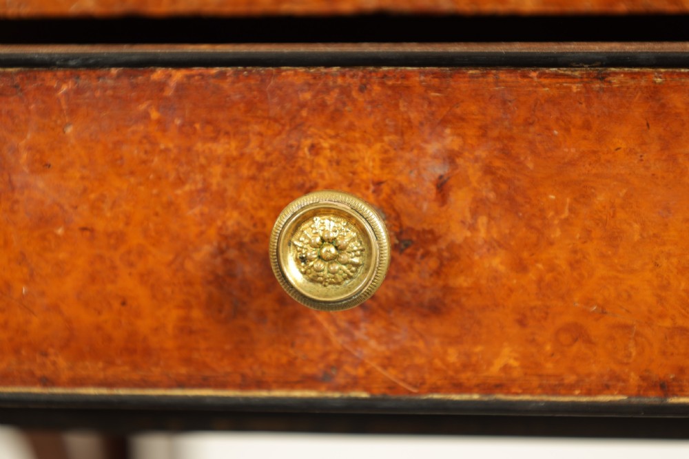 An antique amboyna and rosewood library table featuring a green leather inset top, frieze drawers with brass knobs, trestle legs, and carved lion paw feet. View IX