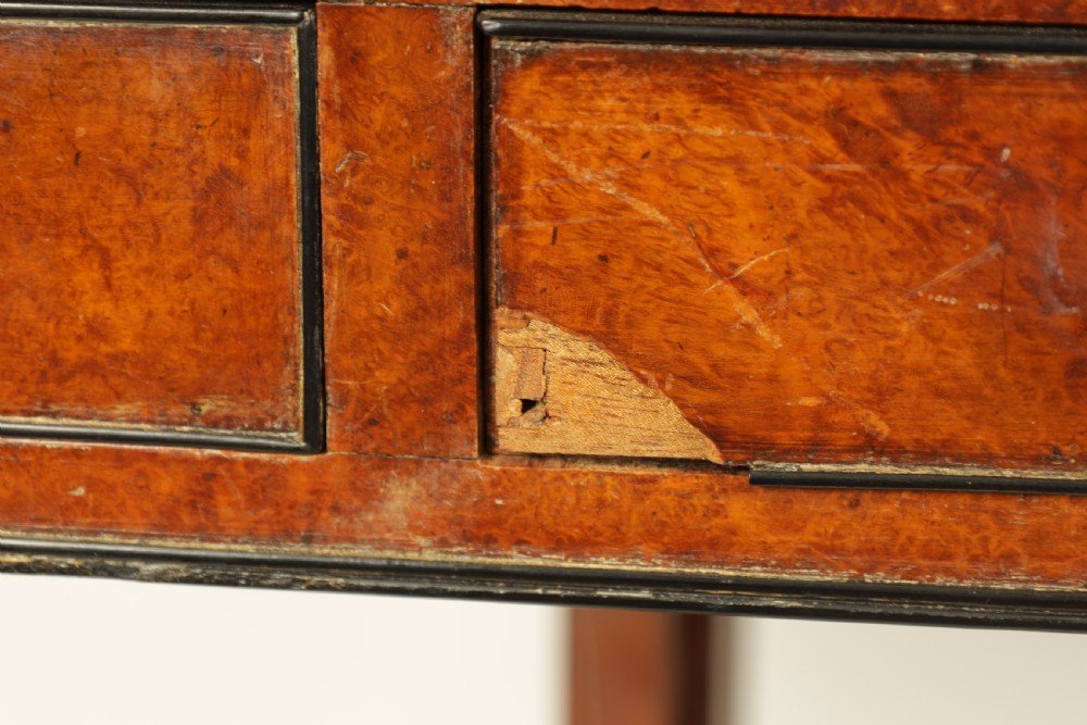 An antique amboyna and rosewood library table featuring a green leather inset top, frieze drawers with brass knobs, trestle legs, and carved lion paw feet. View X