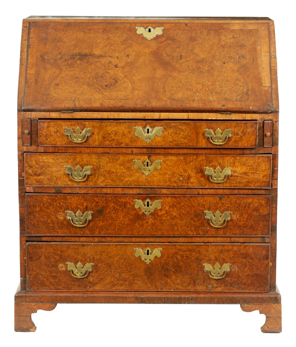 An 18th-century burr walnut bureau featuring a slant-front flap above four graduated drawers with brass handles, resting on bracket feet.