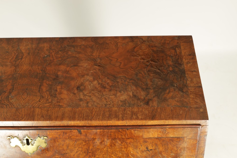 An 18th-century burr walnut bureau featuring a slant-front flap above four graduated drawers with brass handles, resting on bracket feet. View IV