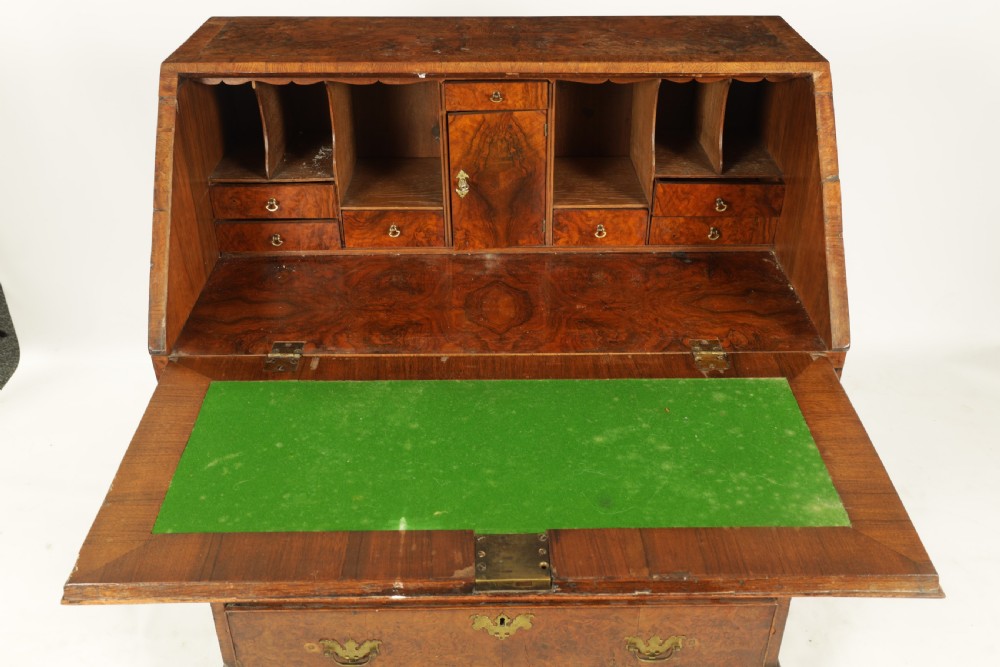 An 18th-century burr walnut bureau featuring a slant-front flap above four graduated drawers with brass handles, resting on bracket feet. View V