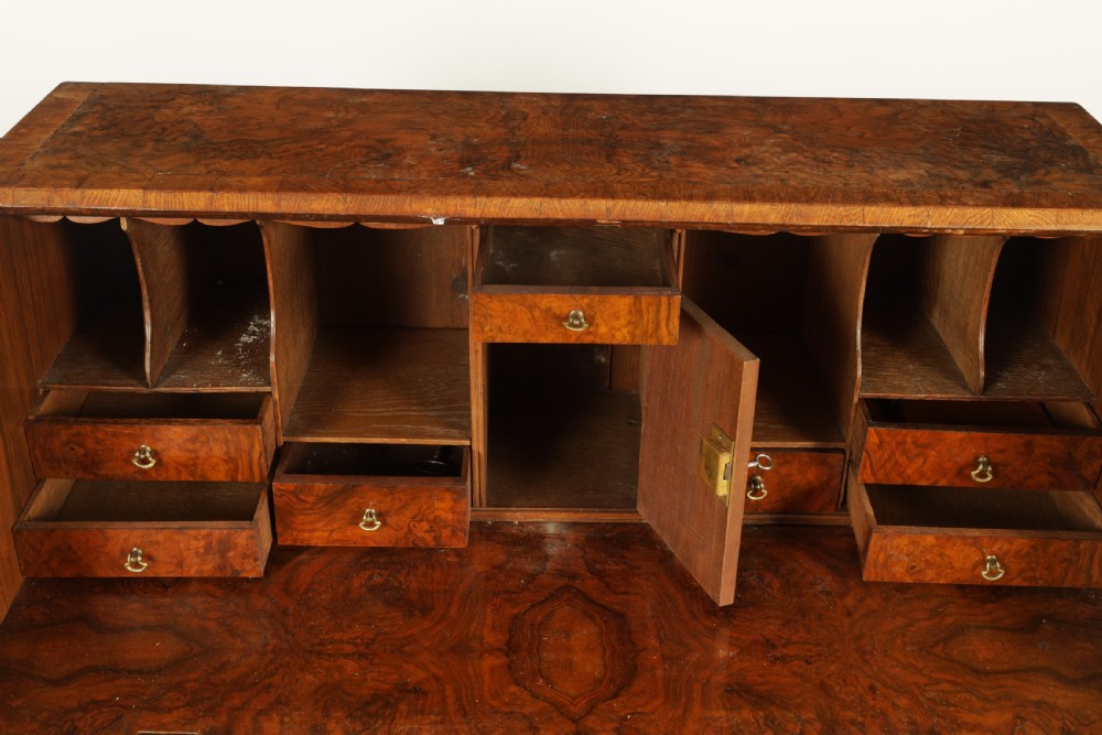 An 18th-century burr walnut bureau featuring a slant-front flap above four graduated drawers with brass handles, resting on bracket feet. View VI