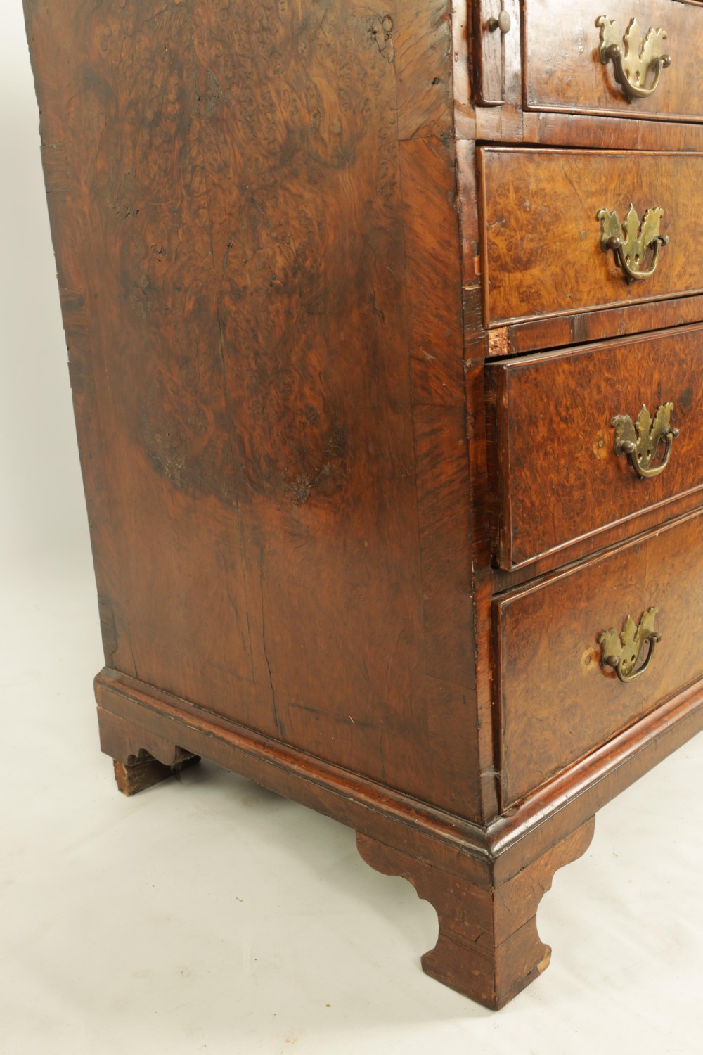 An 18th-century burr walnut bureau featuring a slant-front flap above four graduated drawers with brass handles, resting on bracket feet. View X